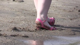 On High Heels and Bare Feet on the Sand, Plump Legs Walk along the Shore.